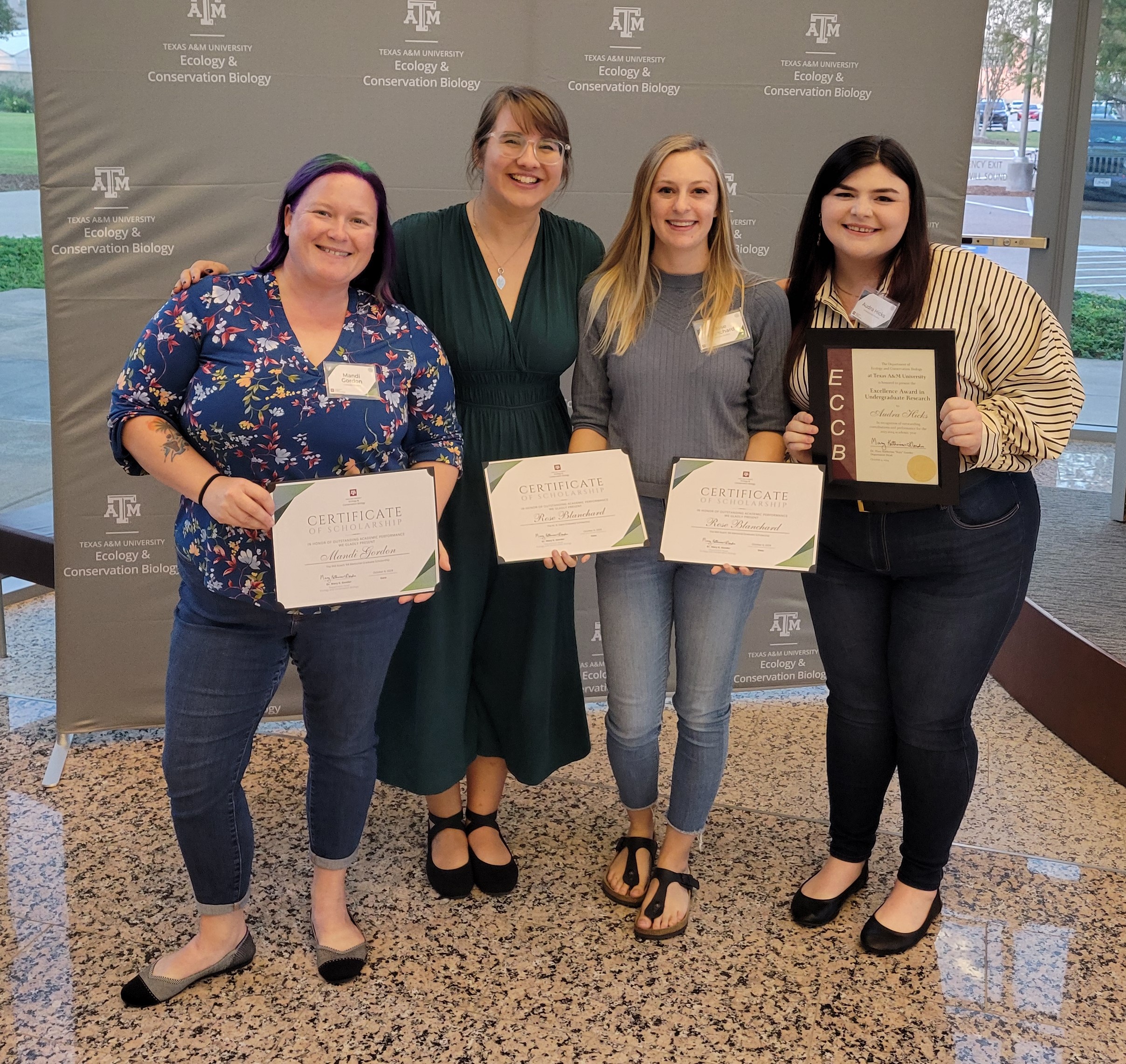 4 people holding awards